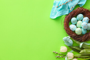 Nest with painted Easter eggs, tulip flowers and willow branches on green background