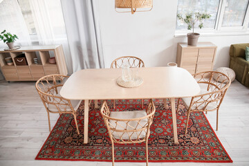 Interior of light dining room with table and vintage carpet