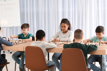 Obraz na płótnie Canvas Little children playing chess during tournament in club
