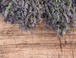 Purple flowers of thyme grass hang from above on a wooden background.