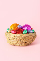 Fototapeta na wymiar Nest with chocolate Easter eggs on pink background