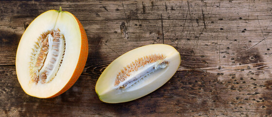 Half and a quarter of a melon in section on a wooden background.