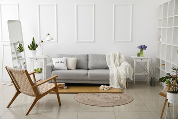 Interior of light living room with sofa, tables and hyacinth flowers in vase