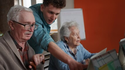 Senior group in retirement home with young instructor learning together in computer class - Powered by Adobe