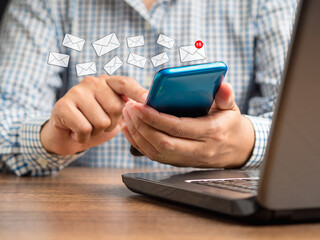 Businessman holding a smartphone receives a new message with email icons