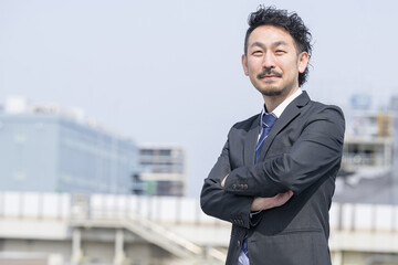 都会で腕を組むサラリーマンのイメージ