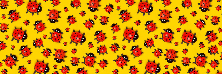Banner with pattern of ladybugs on yellow background, as backdrop or texture. Bright summer wallpaper. Top view Flat lay
