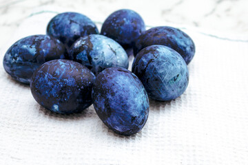 Cosmic colored eggs lie on a white waffle towel on a marble table. Easter eggs on the table