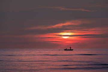 Fishermen set up their fishing gear against the background of a beautiful sunset.