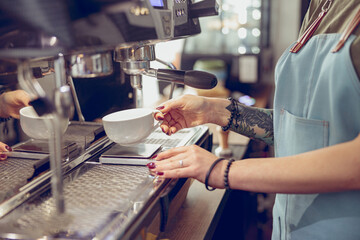 Barista using professional coffee machine in coffeehouse