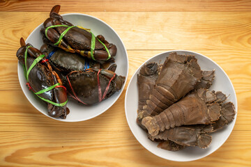 Raw Flathead lobster and Raw Sea crab on white plate, Mantis shrimp and black Crab  on wooden...