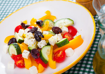 Fototapeta na wymiar Plate of tasty Greek salad with fresh cucumbers, tomatoes, bell pepper and feta cheese