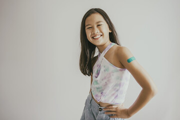 Mixed Asian preteen girl showing her arm with bandage after got vaccinated or inoculation, child immunization, covid omicron vaccine concept - obrazy, fototapety, plakaty