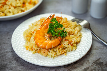 Rice with shrimps on a white plate on the table.