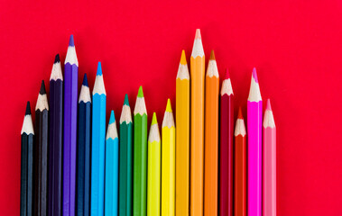 A row of color pencils on red background