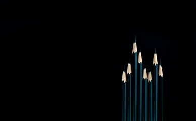 A row of green color pencils on black background
