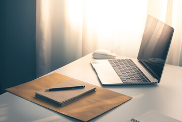 brown paper craft letter and laptop with data chart on white desk, interior of working room, work from home. home interior of open work space with white desk. small home business.