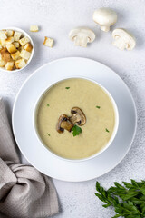 Mushroom cream soup with parsley and croutons on a dark grey, top view. Selective focus.