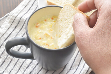 Creamy vegetable soup with bread in a mug.