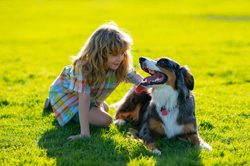 Happy kid and pet dog playing at backyard lawn. Child with pet puppy dog. Happy smiling kid with...