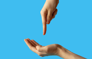 Close-up of women's hands, side view with the palm up, and the second hand points a finger at the palm. isolated on a blue background