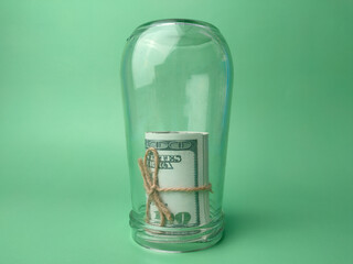 Dollar banknotes on glass jar on a green background with copy space.