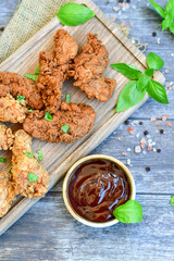 
 Crispy  deep fried   Chicken    strips and Wedges potato. Breaded  with cornflakes chicken  breast fillets  with chilly peppers and fresh   basil on wooden rustic background