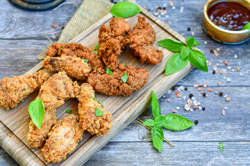 
 Crispy  deep fried   Chicken    strips and Wedges potato. Breaded  with cornflakes chicken  breast fillets  with chilly peppers and fresh   basil on wooden rustic background