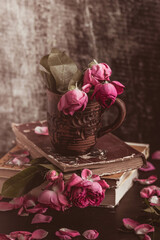 Still life in vintage style: withering roses and old books