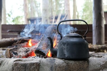 An old metal kettle stands by campfire