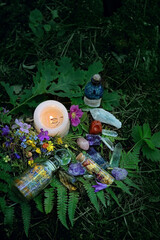 Candle, minerals, magic bottles and pentagram amulet on mysterious natural forest background....