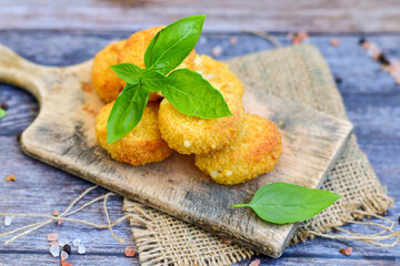 Vegetarian Cheese oven baked Croquette  with  fresh basil on Wooden background. Yellow cheese nuggets