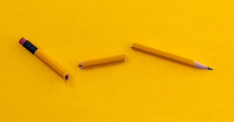 Broken pencil on yellow background