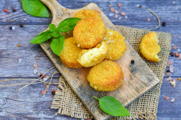 Vegetarian Cheese oven baked Croquette  with  fresh basil on Wooden background. Yellow cheese nuggets