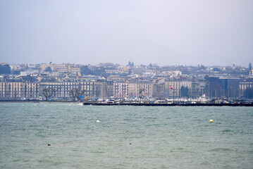Obraz premium Border of Lake Geneva at City of Geneva with cityscape in the background on a gray and cloudy spring day. Photo taken March 18th, 2022, Geneva, Switzerland.