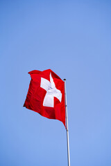 Swiss flag waving on top of building at City of Lausanne on a sunny spring day. Photo taken March 18th, 2022, Lausanne, Switzerland.