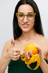 Cellulite is consequence of poor nutrition. Nutritionist holding measuring tape with orange fruit, panorama