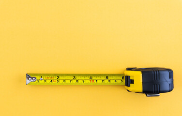 Yellow tape measure on yellow background