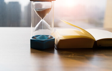 Close-up of hourglass with book on table