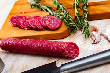 Sliced Catalan dry cured sausage Fuet Nobleza on wooden background. Preferred Spanish meat products