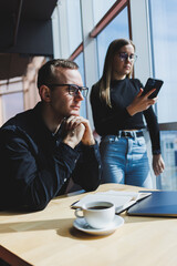 We work together on a business project. Two young business colleagues work on a laptop in a modern large office. Business partners in the office at work