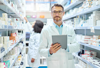 Its a pharmacists best friend. Shot of a mature man using a digital tablet to do inventory in a...