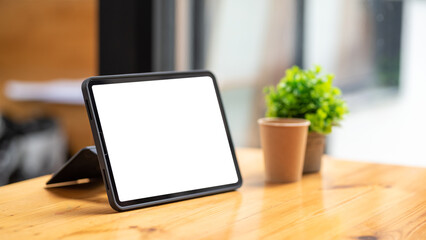 Tablet blank screen on desk and workspace background in modern office.