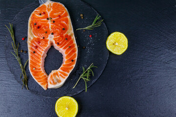 Raw salmon steak with spices on black slate. Top view