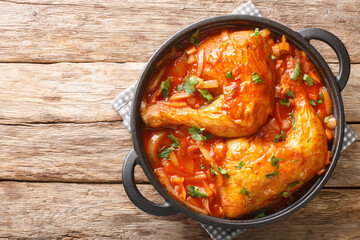 Baked chicken with onion tomato gravy close-up in a pan on the table. horizontal top view from above