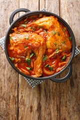 Chicken legs baked in onion tomato sauce close-up in a frying pan on the table. vertical top view from above