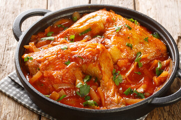 Rustic style baked chicken with spicy onion tomato sauce close-up in a frying pan on the table. horizontal