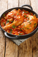 Chicken legs baked in onion tomato sauce close-up in a frying pan on the table. vertical