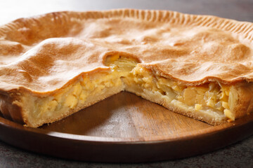 English closed pie with cheese and onions close-up in a plate on the table. Horizontal