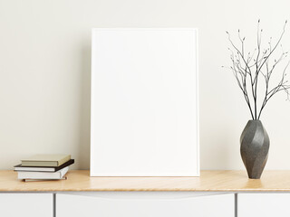 Minimalist vertical white poster or photo frame mockup on wood table with books and vase in a room